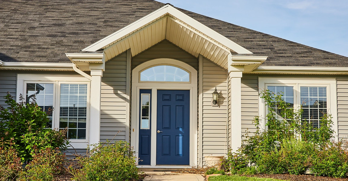 Stylish front door with sidelights and patio doors on a home in Columbus, Ohio, framed by clean vinyl siding.